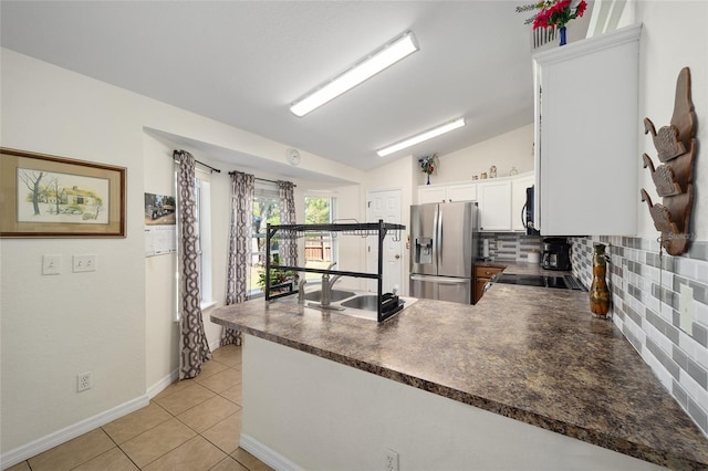 kitchen featuring lofted ceiling, decorative backsplash, kitchen peninsula, stainless steel appliances, and white cabinets