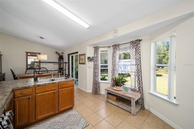 kitchen featuring decorative light fixtures, sink, light tile patterned floors, and vaulted ceiling