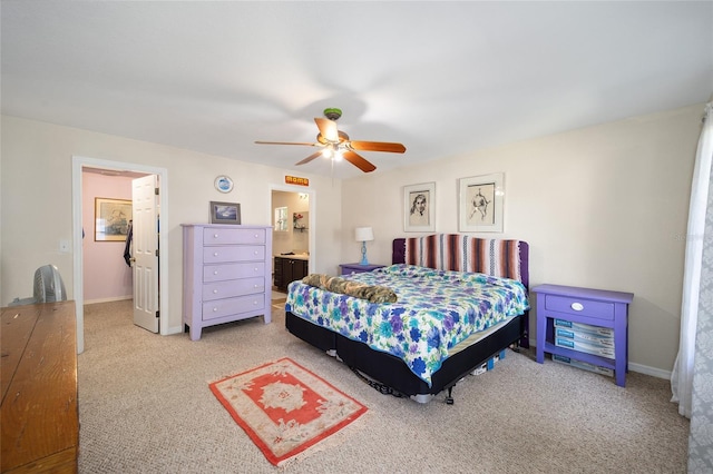 carpeted bedroom with ensuite bath and ceiling fan