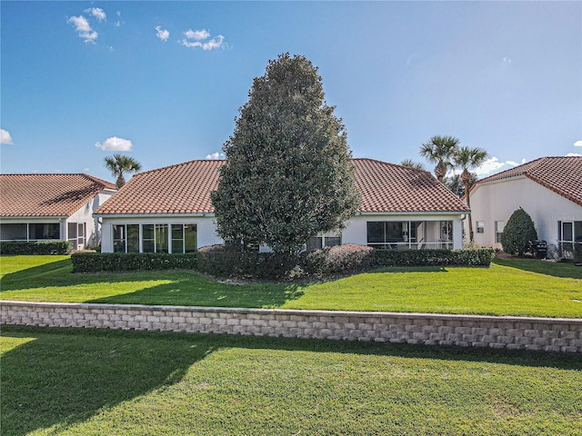 back of property with a tile roof, a yard, and stucco siding