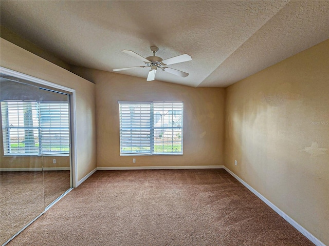 spare room with a textured ceiling, carpet, and baseboards