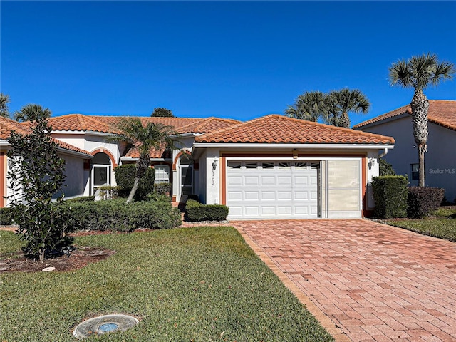 mediterranean / spanish-style home featuring a front lawn and a garage