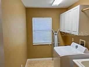 washroom with washer and dryer, cabinet space, and baseboards