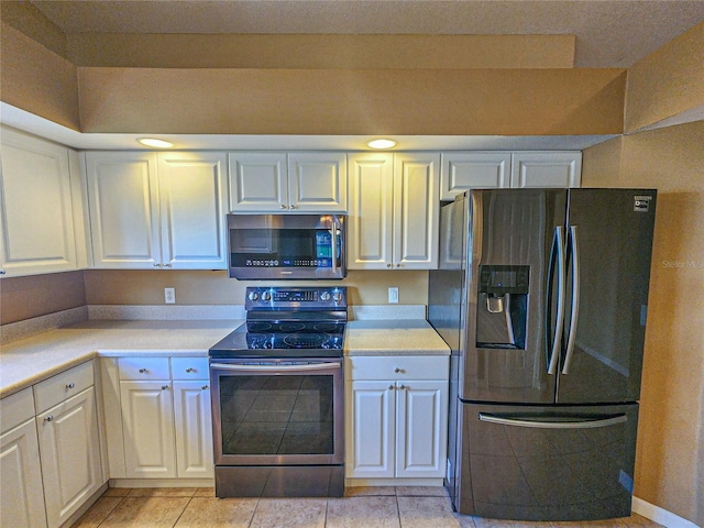 kitchen with light tile patterned floors, white cabinetry, appliances with stainless steel finishes, and light countertops