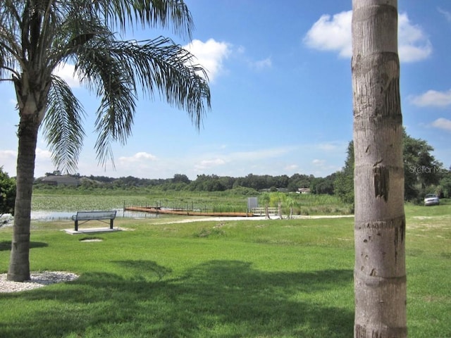 view of community with a water view, a lawn, and a rural view