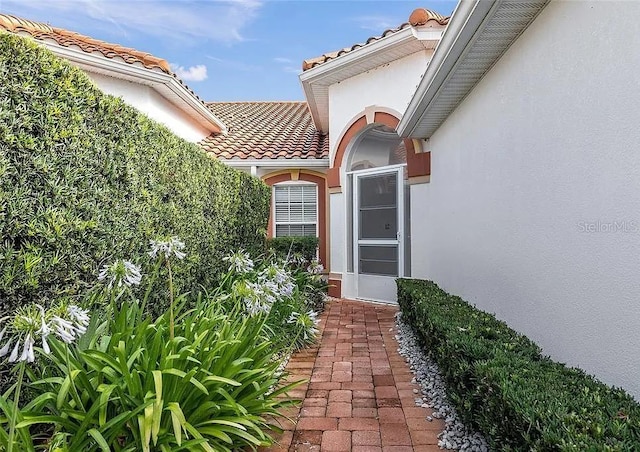 property entrance with a tile roof and stucco siding