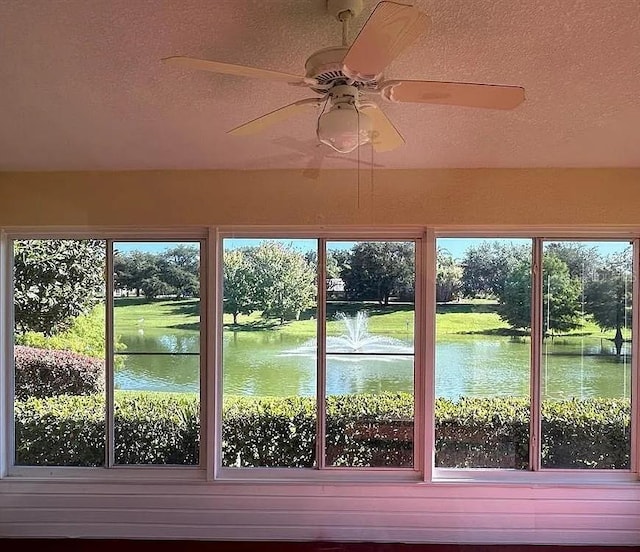 unfurnished sunroom featuring a water view and a ceiling fan