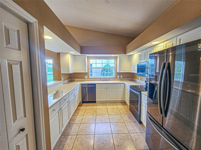 kitchen featuring light tile patterned floors, appliances with stainless steel finishes, vaulted ceiling, light countertops, and a sink