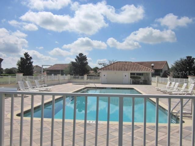 community pool with a patio area and fence