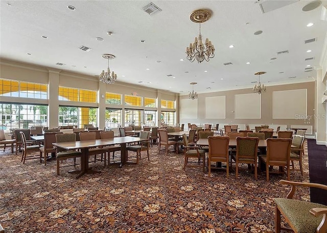 dining room featuring plenty of natural light, visible vents, crown molding, and a notable chandelier