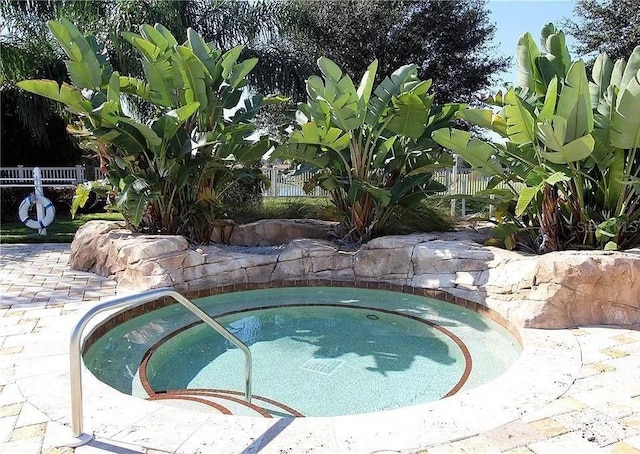 view of swimming pool featuring an in ground hot tub and fence