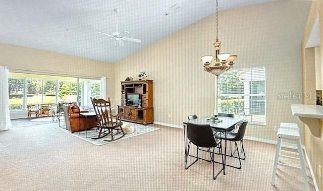 dining area with baseboards, high vaulted ceiling, ceiling fan with notable chandelier, and wallpapered walls