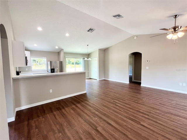 unfurnished living room featuring dark wood-type flooring, arched walkways, visible vents, and vaulted ceiling