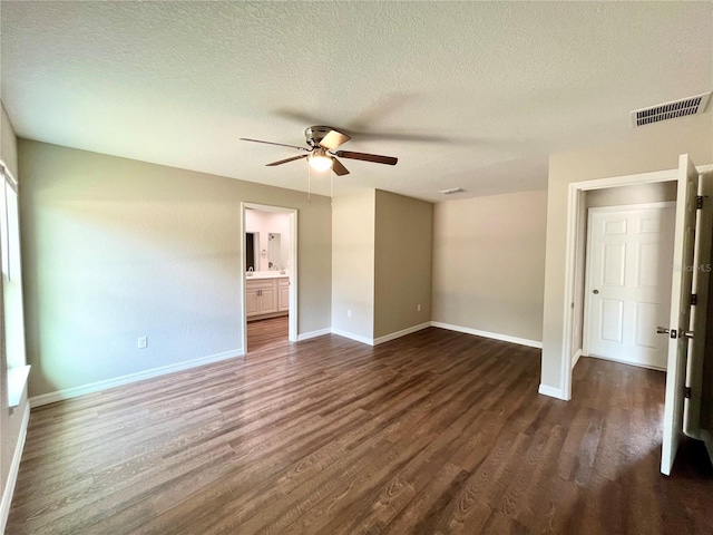 unfurnished bedroom featuring a textured ceiling, dark wood-style flooring, visible vents, and baseboards