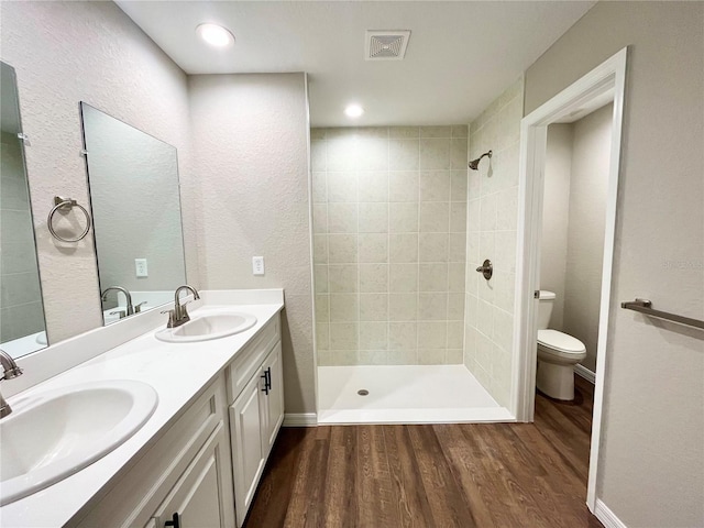 full bathroom with toilet, visible vents, a sink, and wood finished floors