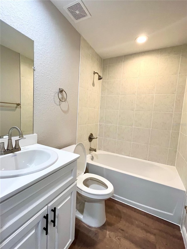 full bath with toilet, wood finished floors, visible vents, vanity, and shower / bathing tub combination