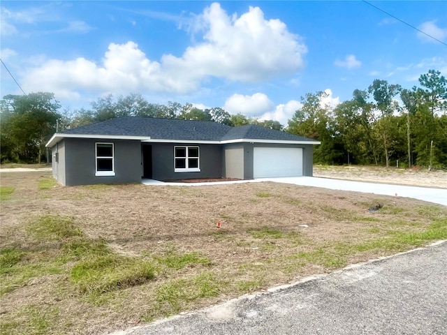 single story home with concrete driveway, a shingled roof, an attached garage, and stucco siding