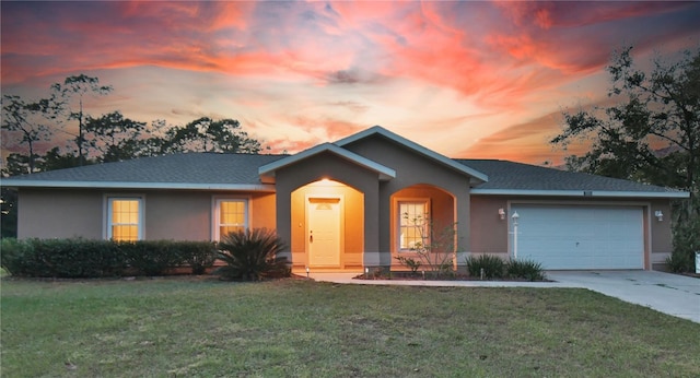 single story home featuring a garage and a lawn