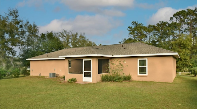 back of property with central air condition unit and a yard