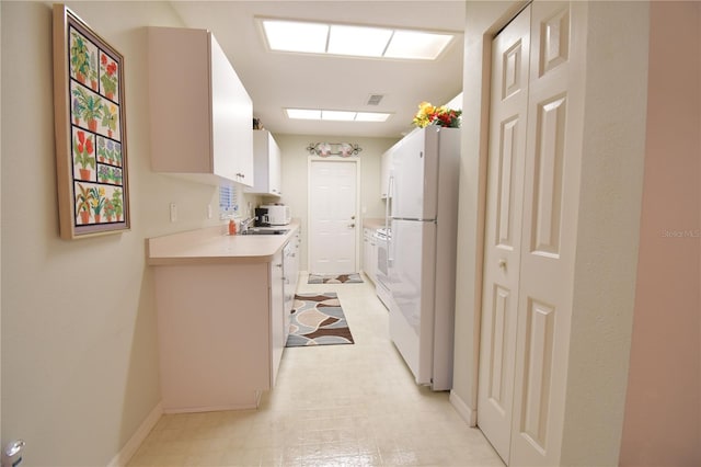 kitchen featuring white appliances, white cabinetry, and sink