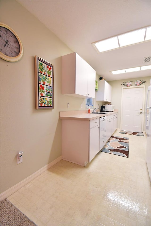 kitchen with white cabinets, sink, and white appliances