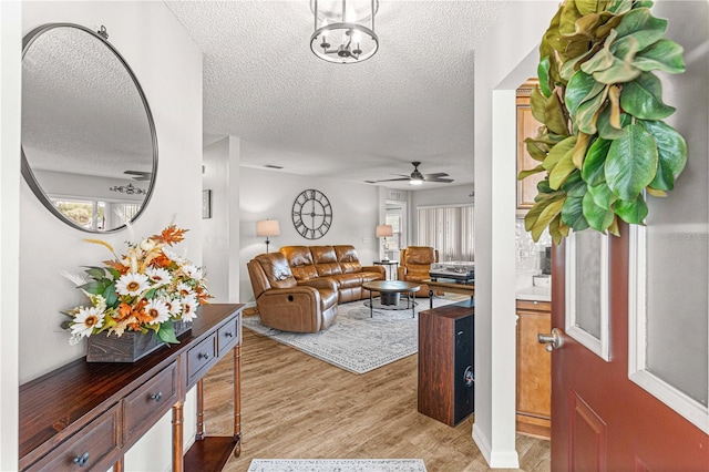 living room with a textured ceiling, light hardwood / wood-style floors, and ceiling fan