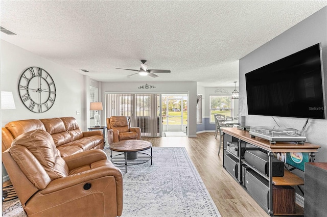 living room featuring a textured ceiling, light hardwood / wood-style floors, and ceiling fan