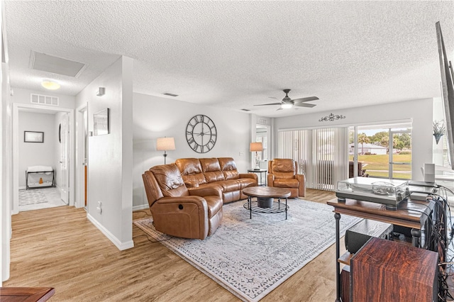 living room featuring a textured ceiling, light wood-type flooring, and ceiling fan