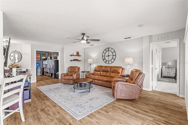 living room featuring a textured ceiling, wood-type flooring, and ceiling fan