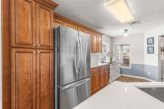 kitchen with wood-type flooring, a textured ceiling, and stainless steel fridge