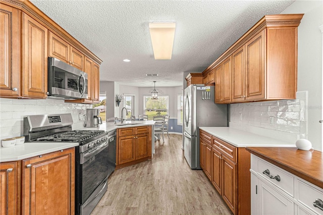 kitchen featuring light hardwood / wood-style flooring, backsplash, sink, appliances with stainless steel finishes, and a textured ceiling