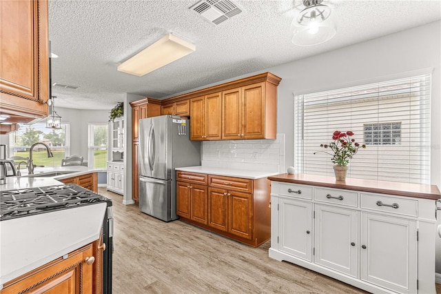 kitchen featuring light hardwood / wood-style floors, stainless steel fridge, sink, and a textured ceiling