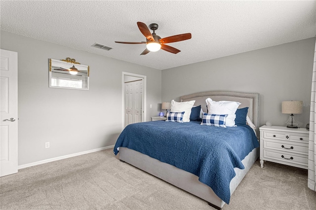 bedroom with a closet, ceiling fan, light carpet, and a textured ceiling