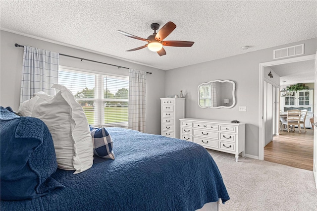 bedroom with a textured ceiling, light hardwood / wood-style floors, and ceiling fan