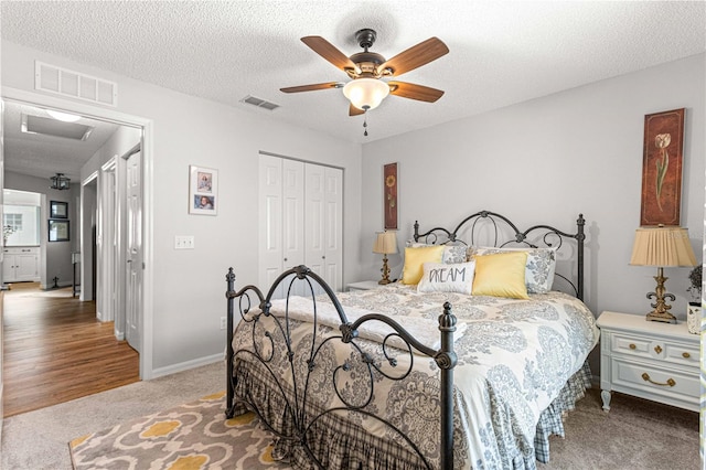 bedroom with a closet, a textured ceiling, carpet flooring, and ceiling fan