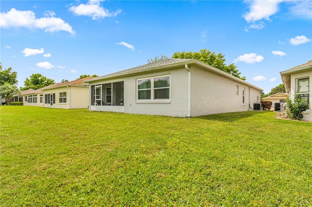 rear view of property featuring a yard, a sunroom, and central AC