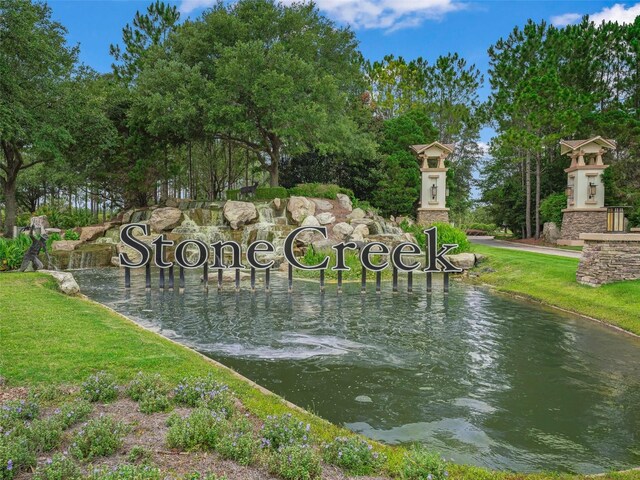 community / neighborhood sign with a lawn and a water view