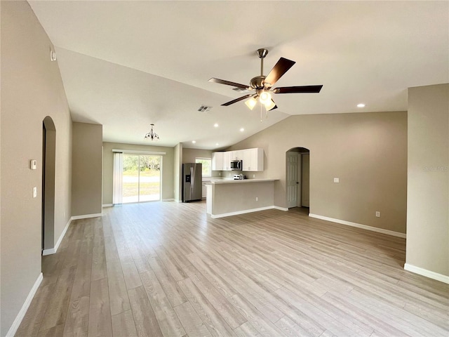 unfurnished living room with visible vents, arched walkways, a ceiling fan, vaulted ceiling, and light wood-style floors