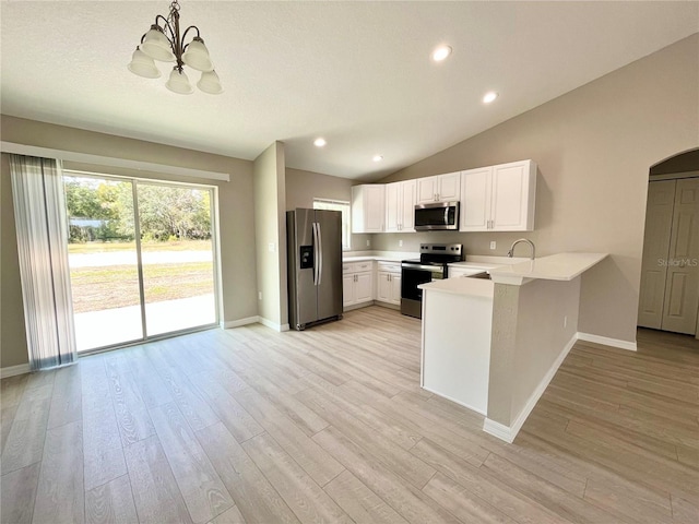 kitchen featuring stainless steel appliances, a peninsula, white cabinetry, light countertops, and decorative light fixtures