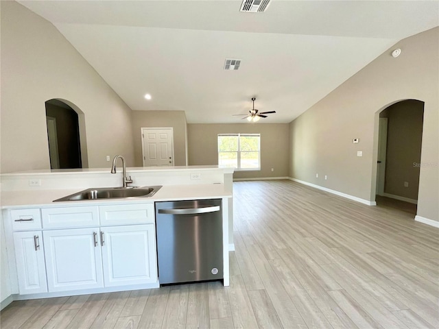 kitchen with arched walkways, white cabinets, dishwasher, light countertops, and a sink