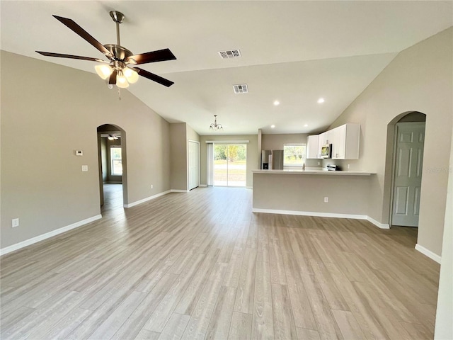 unfurnished living room featuring arched walkways, visible vents, light wood-style flooring, and baseboards