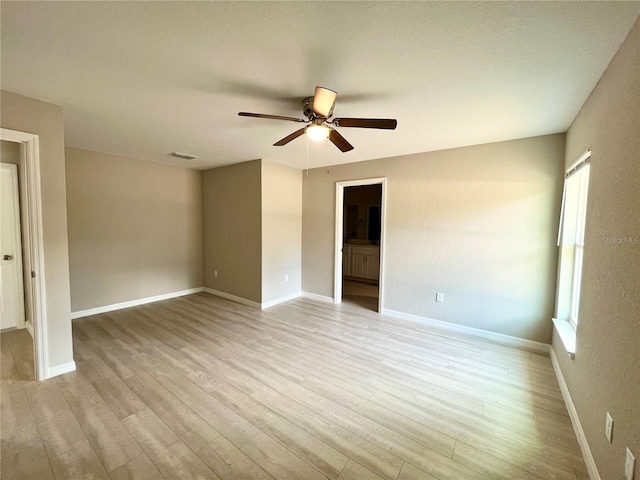 spare room with light wood-style floors, visible vents, ceiling fan, and baseboards