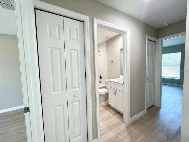 bathroom featuring toilet, wood finished floors, bathtub / shower combination, vanity, and a closet