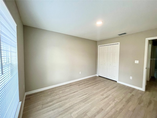 unfurnished bedroom with a closet, visible vents, light wood-style flooring, and baseboards