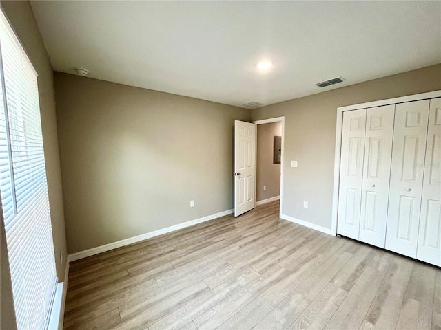 unfurnished bedroom with baseboards, a closet, visible vents, and light wood-style floors