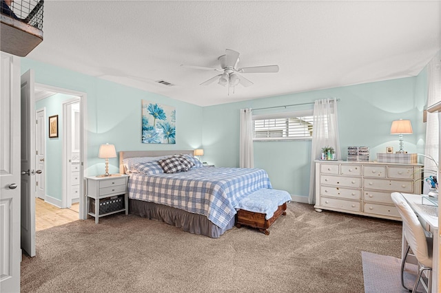 bedroom featuring a textured ceiling, light colored carpet, and ceiling fan