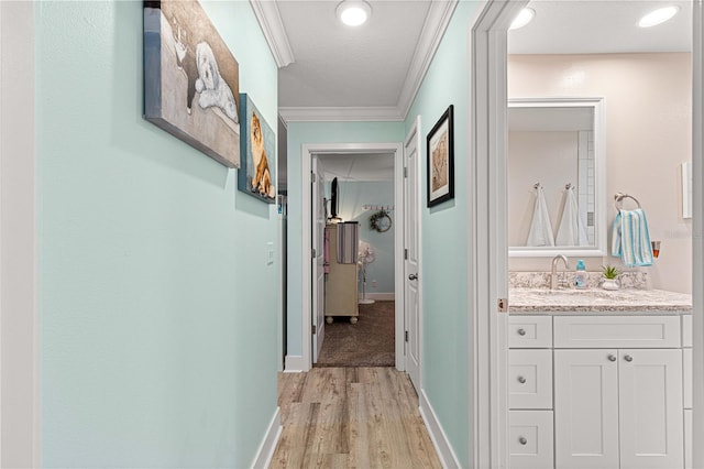 hall featuring light hardwood / wood-style flooring, ornamental molding, sink, and a textured ceiling