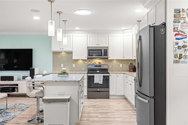 kitchen with appliances with stainless steel finishes, a kitchen bar, hanging light fixtures, white cabinetry, and light hardwood / wood-style floors