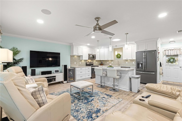 living room with ceiling fan, ornamental molding, and light hardwood / wood-style floors