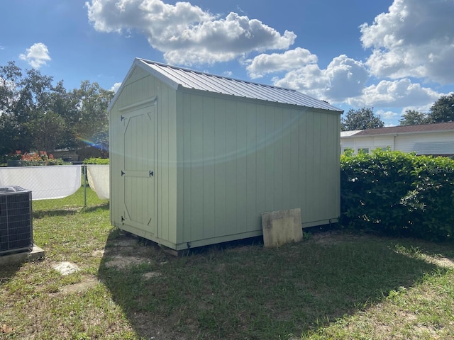 view of outdoor structure featuring a yard and central AC